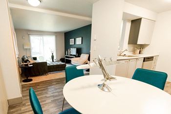 a kitchen and living room with a white table and blue chairs at Aero Apartments, Tacoma, Washington
